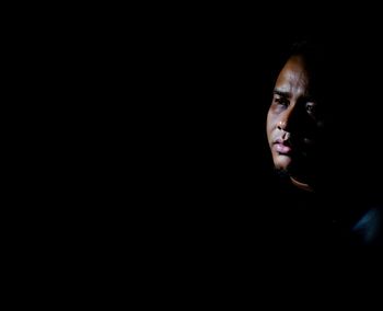 Portrait of man looking away against black background