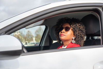 Pretty african woman in a car doing makeup while standing in a traffic jam