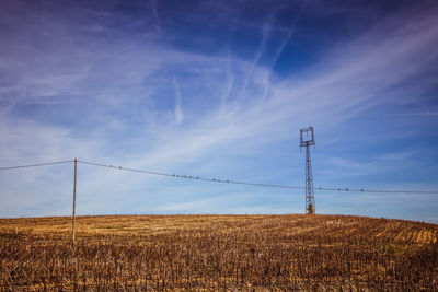 Electricity pylon on field against sky