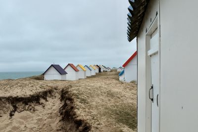 Beach huts by buildings against sky