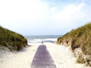 Scenic view of calm beach against cloudy sky