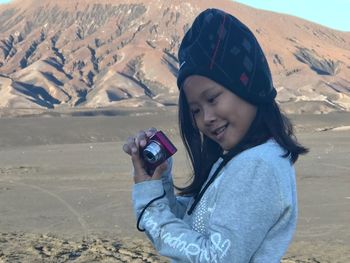 Young woman photographing on snow covered landscape