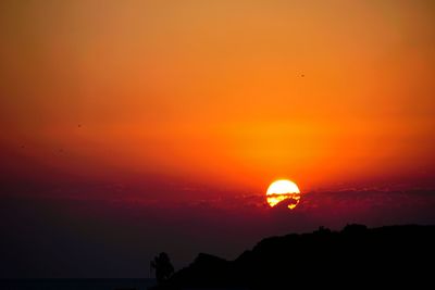 Scenic view of silhouette mountain against orange sky