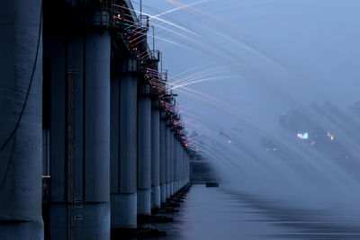 Low angle view of water flowing from bridge in river against sky at dusk