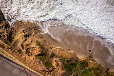View of ocean water coming up on the beach right up against the cliffs in la jolla cove. 