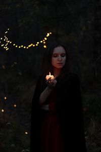 Young woman standing against trees and plants