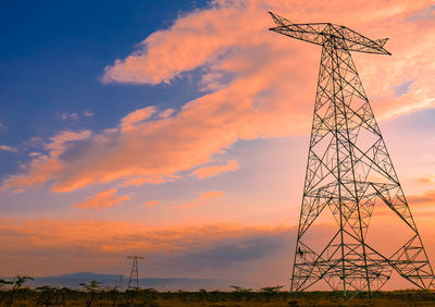 Low angle view of electricity pylon against sky during sunset