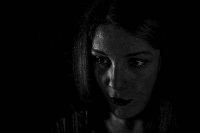 Close-up of thoughtful young woman looking away against black background