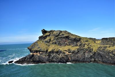 Rock formations by sea against blue sky