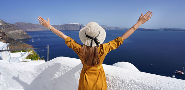 Europe travel vacation woman with arms up looking santorini caldera in greece. 