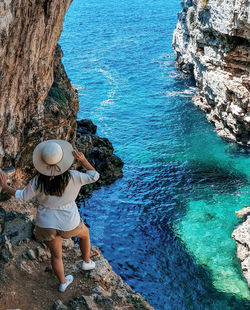 Young woman from behind. standing on cliff above sea. view, summer, vacation.