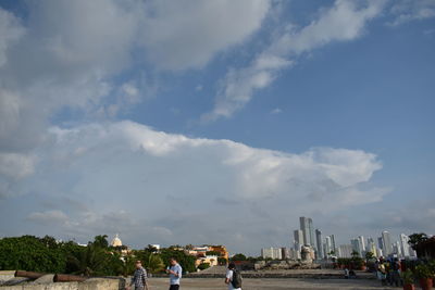 People at town square against cloudy sky