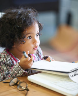 Cute girl holding pen looking away