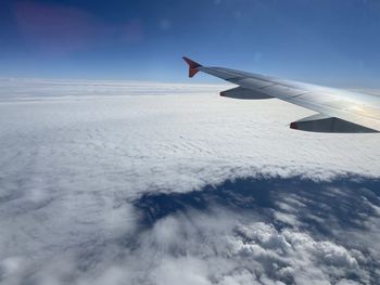 Airplane flying over snowcapped mountain against sky