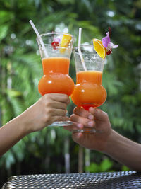 Cropped hands toasting drinks outdoors