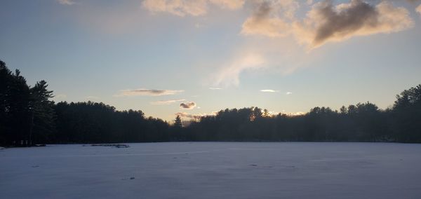 Scenic view of snow covered landscape against sky at sunset