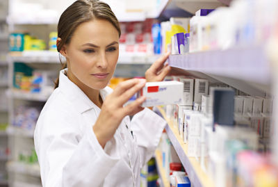 Female pharmacist examining medicine at drug store