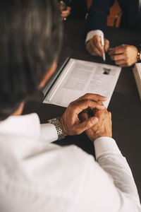 High angle view of businessman discussing over document in meeting at office