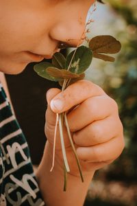 Close-up of boy smelling plant outdoors
