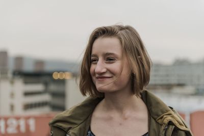 Portrait of smiling young woman standing against sky