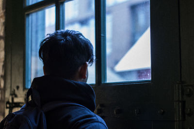Rear view of man looking through window