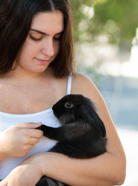 Young beautiful woman holding a black rabbit pet animal. domestic animal caring