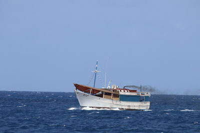 Boat sailing in sea against clear blue sky