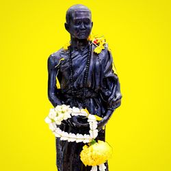 Close-up of buddha statue against yellow wall