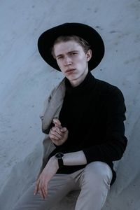 Portrait of young man sitting on hat