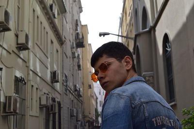 Young man standing against buildings in city