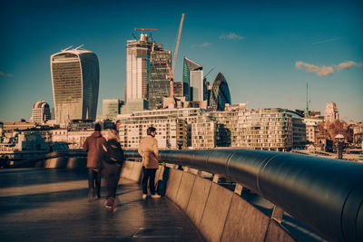 People by railing against buildings and sky in city