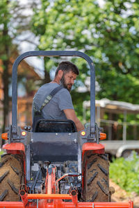 A man on a mini-excavator levels a piece of land, loosens the soil.