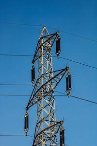 Low angle view of electricity pylon against blue sky