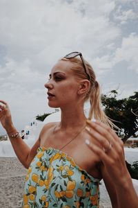 Young woman standing at beach against sky