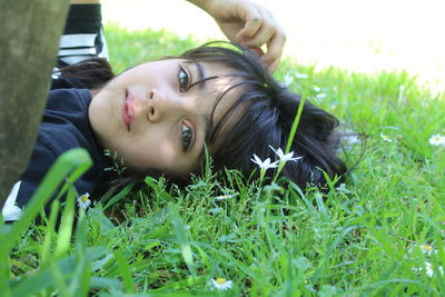 Portrait of cute girl lying on grassy field