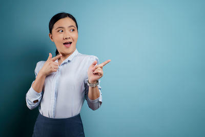 Portrait of young woman standing against gray background