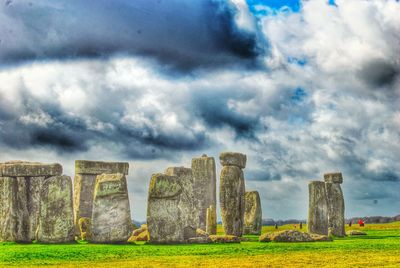 Old ruins on field against cloudy sky