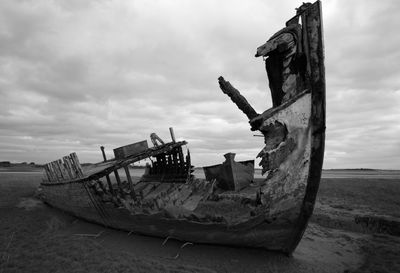 Abandoned boat on beach against sky