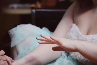 Midsection of teenage girl with blue nail polish at home