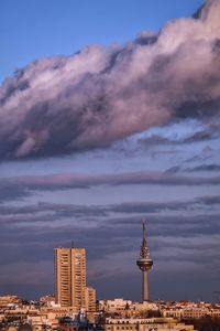 Buildings in city against cloudy sky