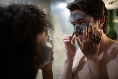 Black woman helping boyfriend with skin care routine