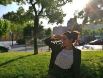 Young woman shielding eyes while standing on field