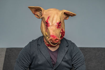 Portrait of young man wearing mask against wall