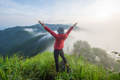 Rear view of woman standing on mountain against sky