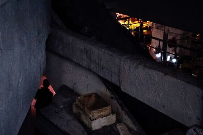 High angle view of woman standing by illuminated building at night