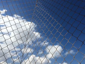 Low angle view of chainlink fence against blue sky