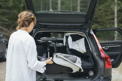 Woman loading pram into car boot