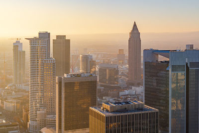 Modern buildings in city against sky during sunset