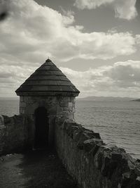 Built structure by sea against sky