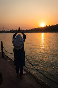 Young indian girl praying the holy ganges river and sun setting at horizon at river bank